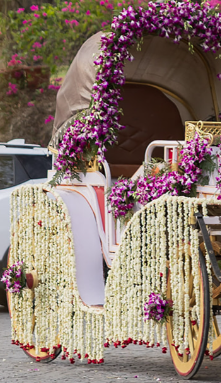 A wedding baggi decorated with cascading white and purple flowers